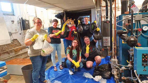 Photo of library staff posing with various garbage bags in their hands, taken during a trash audit.